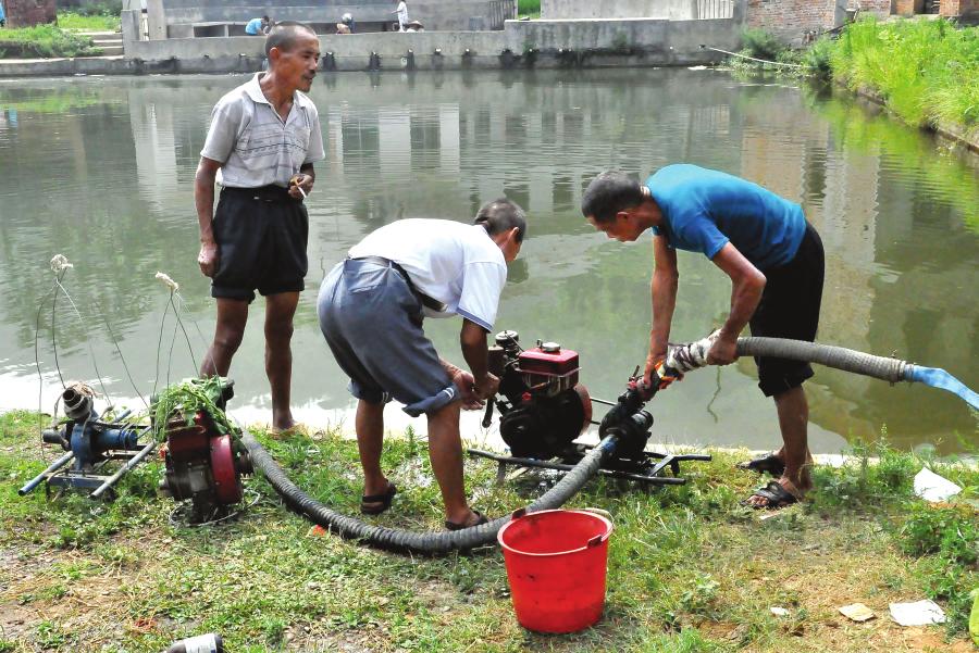 邵阳县小溪市乡岩门前村的几个农民在水塘边抽水灌田